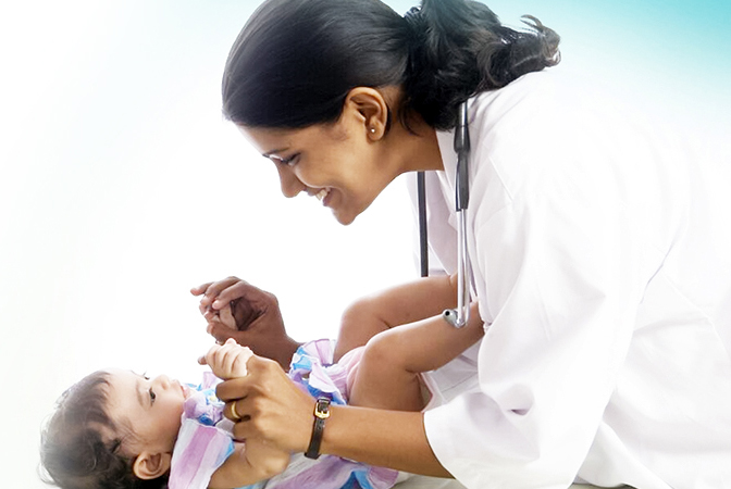 A  female doctor is holding the hands of a baby.